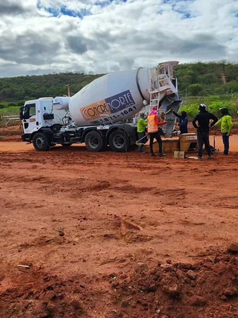 Caminhão betoneira e equipe em concretagem no loteamento